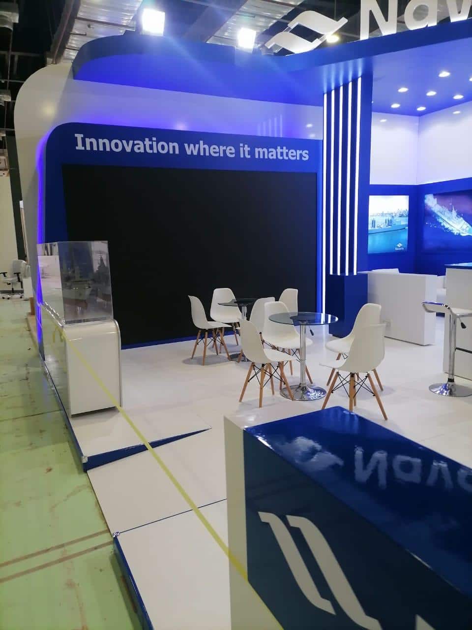 Backlit vertical fin façade under blue-wash lighting, Equal's stand for Navantia
